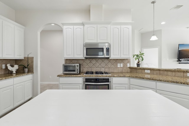 kitchen with backsplash, appliances with stainless steel finishes, hanging light fixtures, and white cabinetry