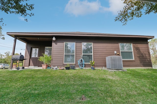 rear view of house featuring a lawn and cooling unit