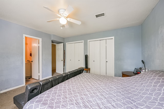 bedroom with ceiling fan, ensuite bath, two closets, and light colored carpet