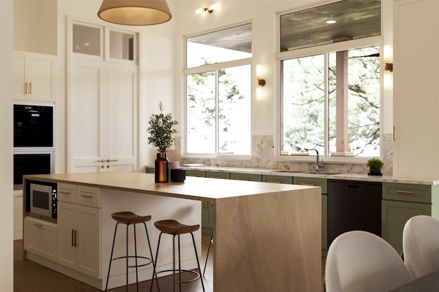 kitchen with white cabinetry, stainless steel microwave, sink, and a center island