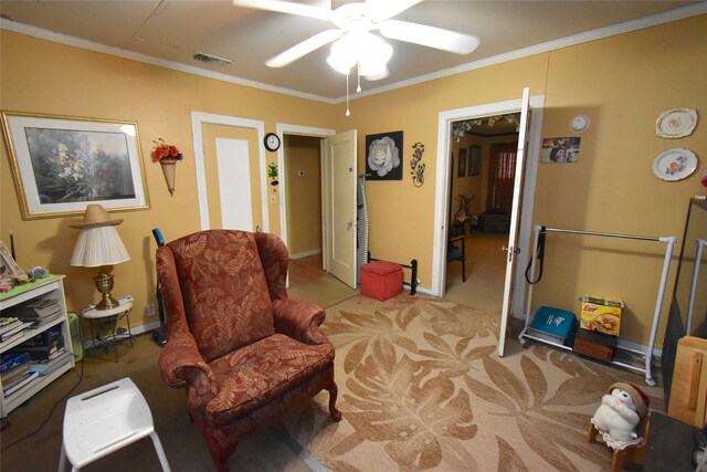 sitting room featuring ceiling fan, ornamental molding, and carpet floors