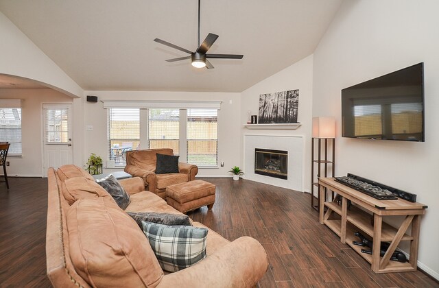 living room with high vaulted ceiling, ceiling fan, a tile fireplace, and dark hardwood / wood-style floors