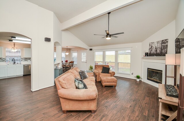 living room with high vaulted ceiling, dark hardwood / wood-style flooring, sink, and a tile fireplace