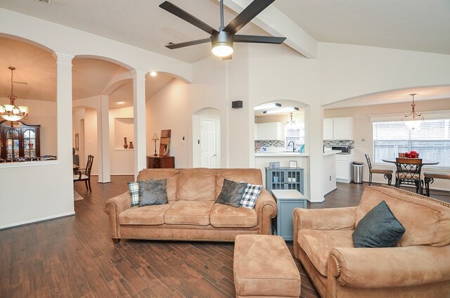 living room with lofted ceiling with beams, ceiling fan with notable chandelier, sink, and dark hardwood / wood-style flooring