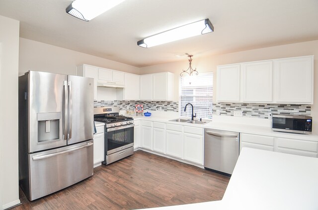 kitchen with sink, appliances with stainless steel finishes, dark hardwood / wood-style floors, white cabinets, and decorative backsplash