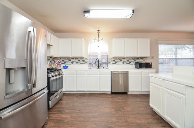 kitchen with stainless steel appliances, white cabinets, sink, dark hardwood / wood-style floors, and pendant lighting