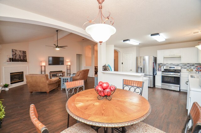 dining room featuring ceiling fan, dark hardwood / wood-style floors, vaulted ceiling with beams, and decorative columns