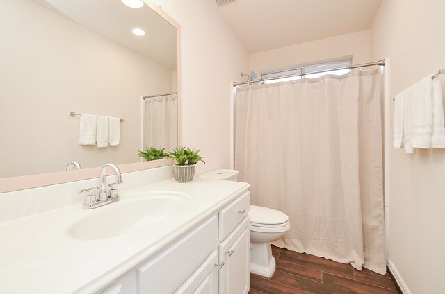 bathroom featuring toilet, vanity, wood-type flooring, and walk in shower