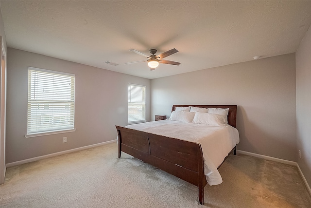 carpeted bedroom featuring ceiling fan and a textured ceiling