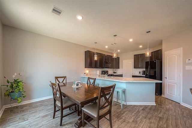 dining room featuring a textured ceiling, sink, and light wood-type flooring