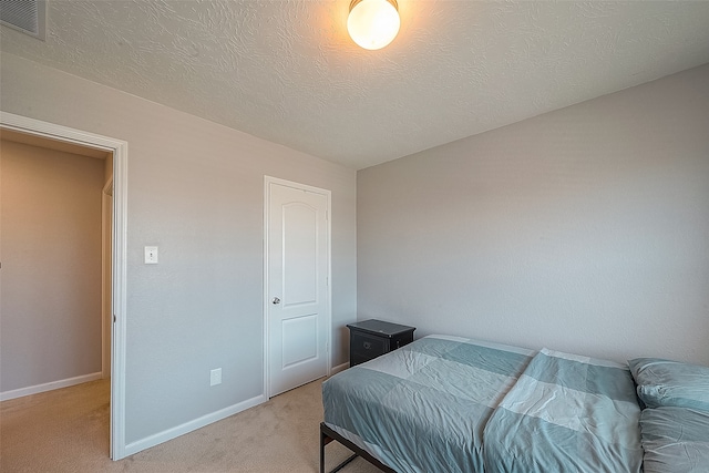 bedroom with light colored carpet and a textured ceiling