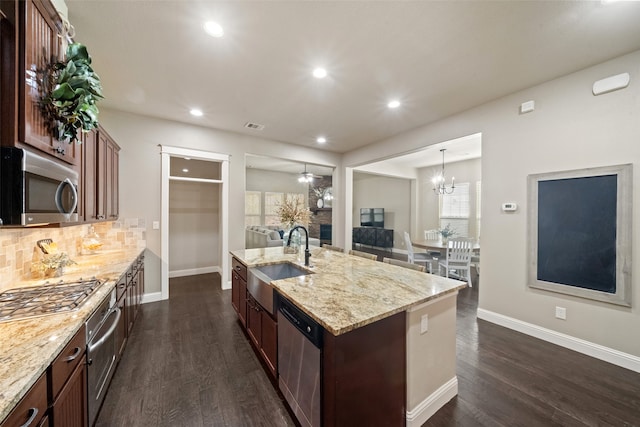 kitchen featuring sink, hanging light fixtures, stainless steel appliances, dark hardwood / wood-style floors, and a kitchen island with sink