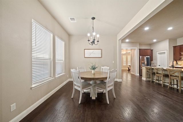 dining area featuring dark wood-type flooring and an inviting chandelier