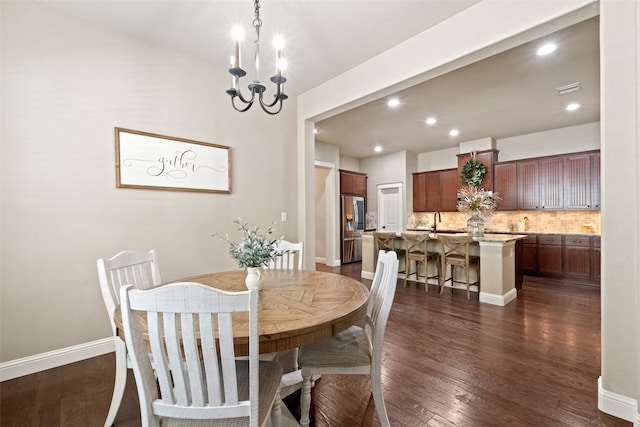 dining room featuring an inviting chandelier, sink, and dark wood-type flooring