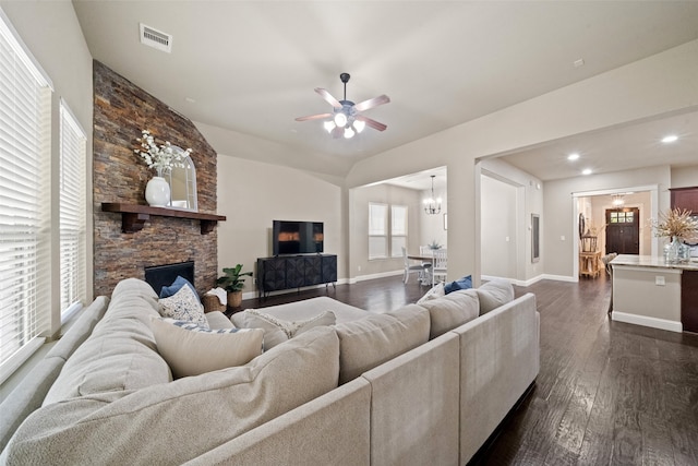 living room with ceiling fan with notable chandelier, a fireplace, and dark hardwood / wood-style floors