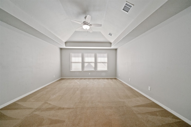 carpeted empty room featuring vaulted ceiling, a tray ceiling, and ceiling fan