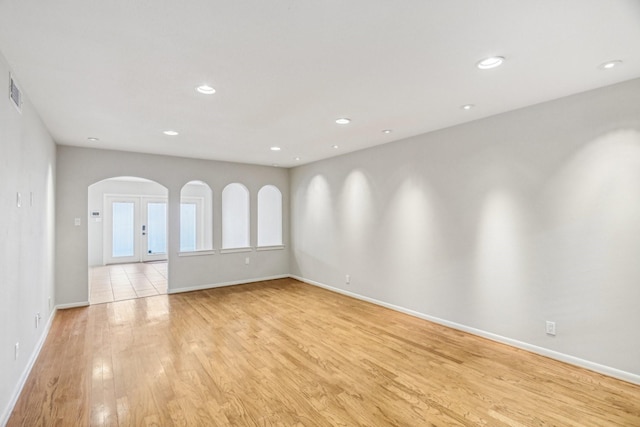 spare room featuring french doors and light hardwood / wood-style flooring