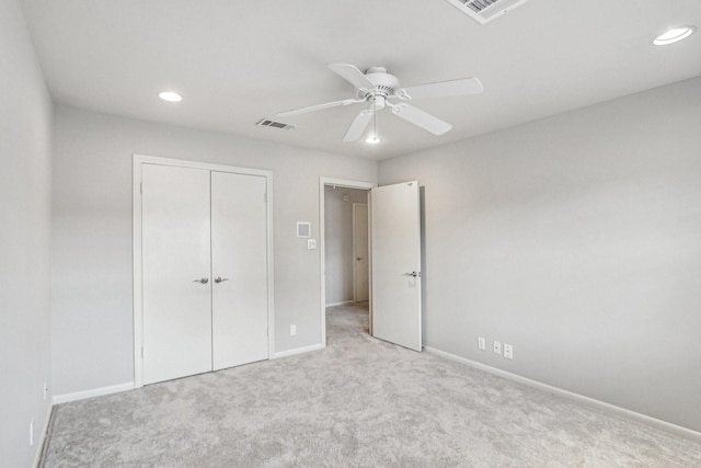 unfurnished bedroom with ceiling fan, light colored carpet, and a closet