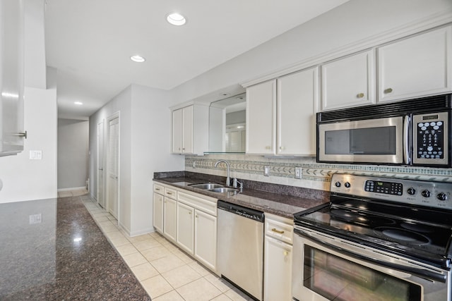 kitchen featuring appliances with stainless steel finishes, white cabinets, sink, and dark stone counters