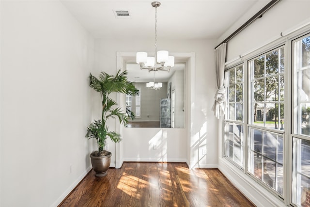 unfurnished dining area featuring an inviting chandelier and dark hardwood / wood-style flooring