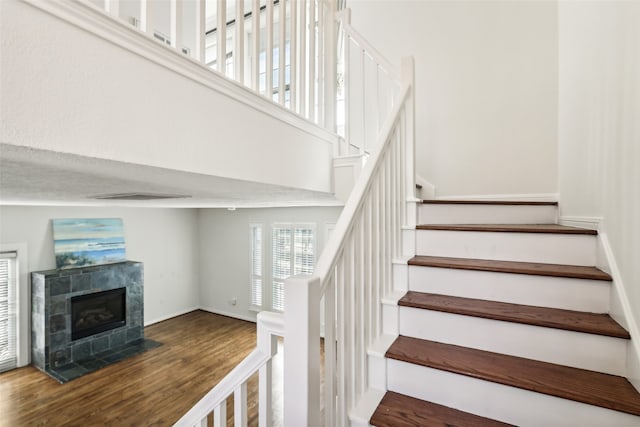 staircase with hardwood / wood-style floors and a fireplace