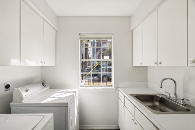 laundry area featuring independent washer and dryer, cabinets, and sink