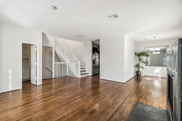 unfurnished living room featuring a notable chandelier and dark hardwood / wood-style floors