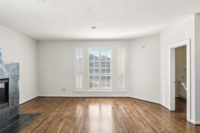 unfurnished living room with dark hardwood / wood-style floors, a textured ceiling, and a tile fireplace