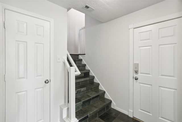 stairs with tile patterned floors and a textured ceiling