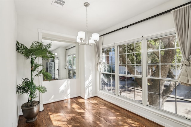 unfurnished dining area featuring a wealth of natural light, wood-type flooring, and an inviting chandelier