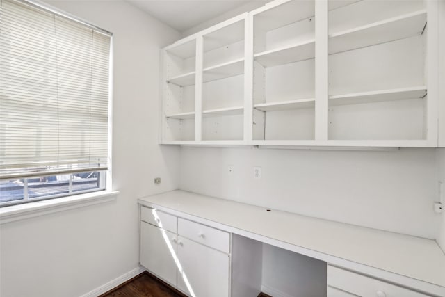 unfurnished office featuring built in desk and dark wood-type flooring