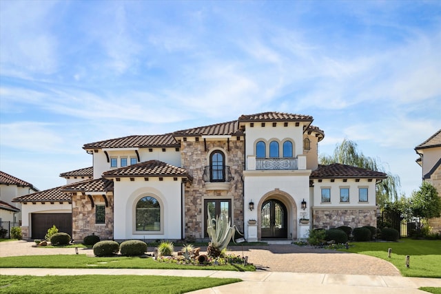 mediterranean / spanish house with french doors, a garage, and a front lawn