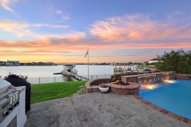 pool at dusk with a lawn, a water view, a boat dock, a grill, and a patio area