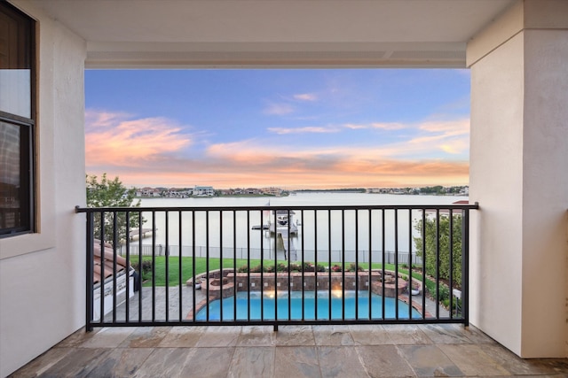 balcony at dusk featuring a water view