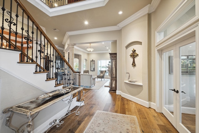 foyer featuring french doors, hardwood / wood-style flooring, ornate columns, and crown molding