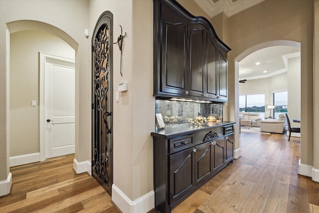 corridor with light hardwood / wood-style flooring and ornamental molding