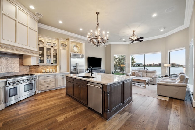 kitchen featuring sink, an island with sink, cream cabinetry, premium appliances, and dark hardwood / wood-style flooring