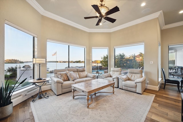 living room with crown molding, a water view, wood-type flooring, and ceiling fan