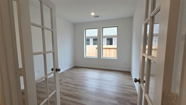 unfurnished room featuring french doors and light wood-type flooring