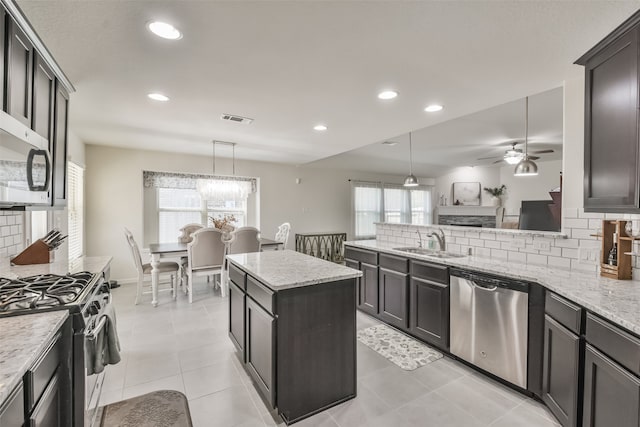 kitchen with appliances with stainless steel finishes, hanging light fixtures, tasteful backsplash, and plenty of natural light