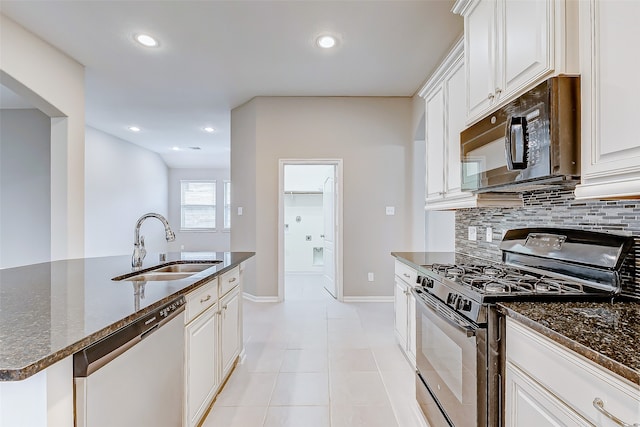 kitchen featuring decorative backsplash, appliances with stainless steel finishes, white cabinetry, and dark stone countertops