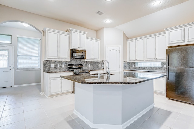 kitchen featuring white cabinets, vaulted ceiling, a kitchen island with sink, and black appliances