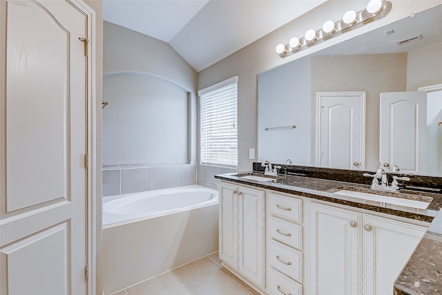 bathroom with tile patterned floors, vanity, vaulted ceiling, and a tub