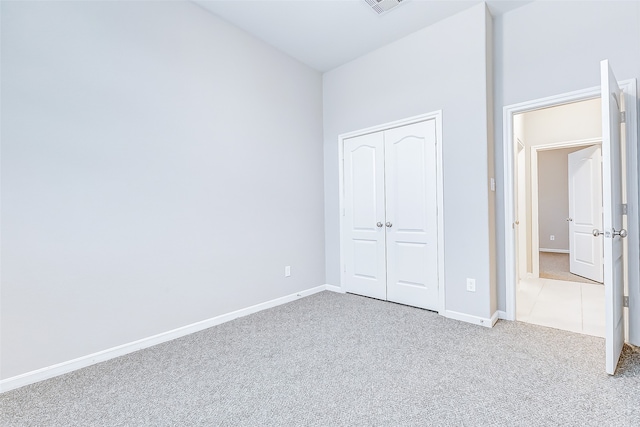 unfurnished bedroom with a closet and light colored carpet