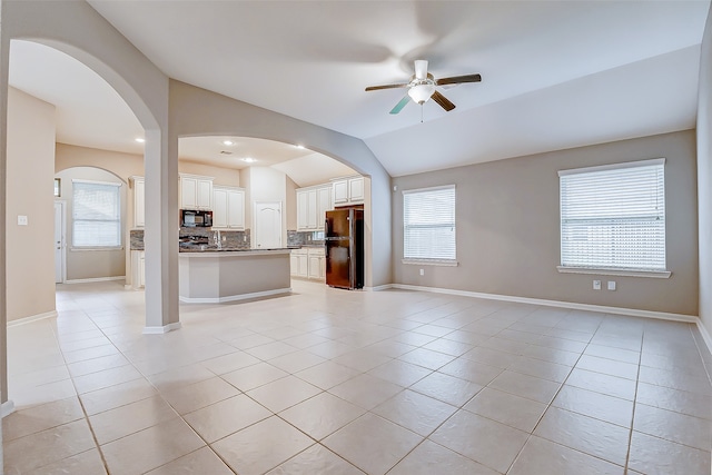 unfurnished living room with vaulted ceiling, ceiling fan, and light tile patterned flooring