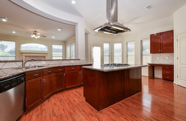 kitchen featuring island range hood, light stone counters, appliances with stainless steel finishes, ceiling fan, and light hardwood / wood-style flooring