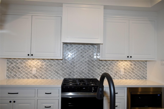 kitchen featuring white cabinets, high end stove, and backsplash