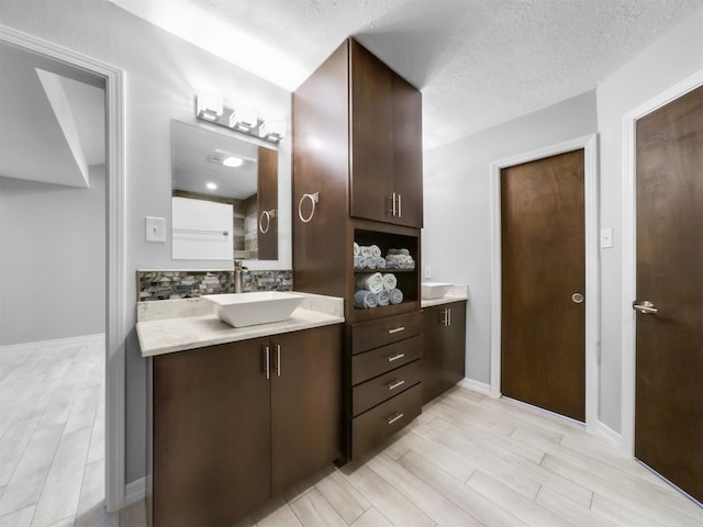 bathroom featuring vanity, backsplash, a textured ceiling, and wood-type flooring