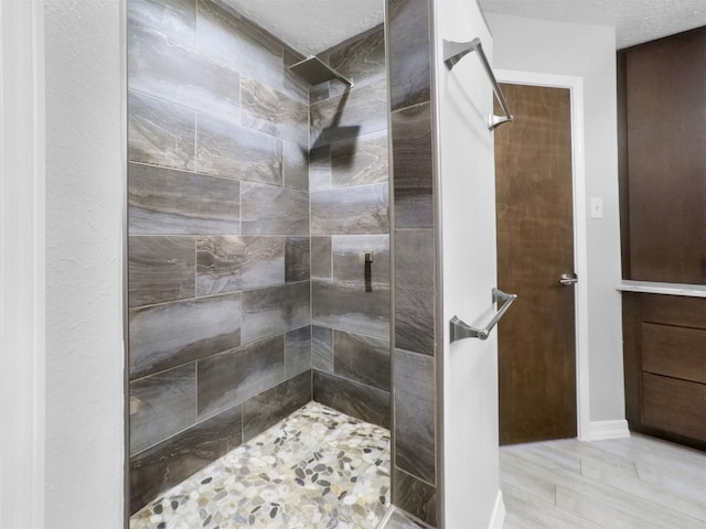 bathroom with a tile shower, a textured ceiling, and hardwood / wood-style flooring