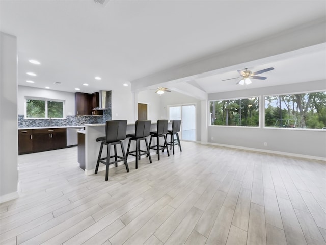 kitchen featuring wall chimney range hood, light wood-type flooring, and plenty of natural light